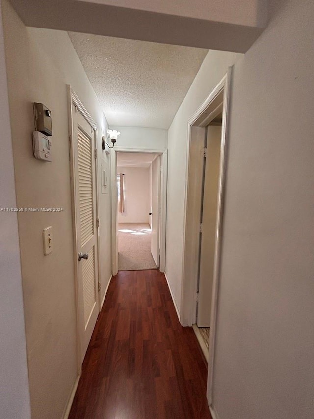 hall featuring dark hardwood / wood-style flooring and a textured ceiling