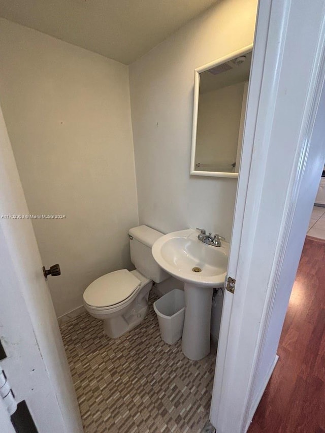 bathroom with hardwood / wood-style flooring and toilet