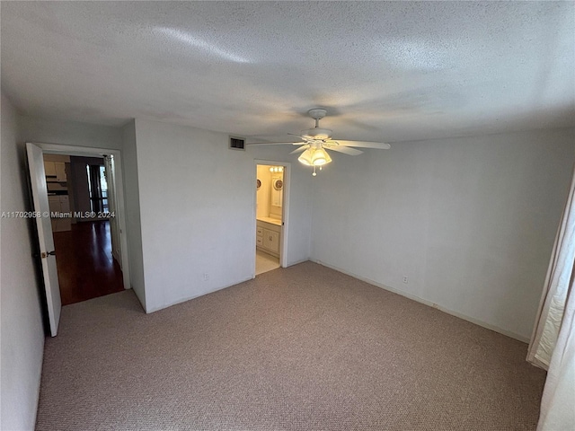 unfurnished bedroom with ceiling fan, ensuite bathroom, light colored carpet, and a textured ceiling