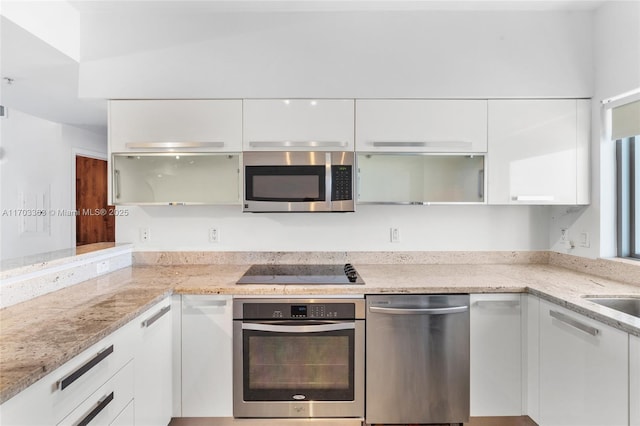 kitchen with light stone counters, stainless steel appliances, and white cabinets