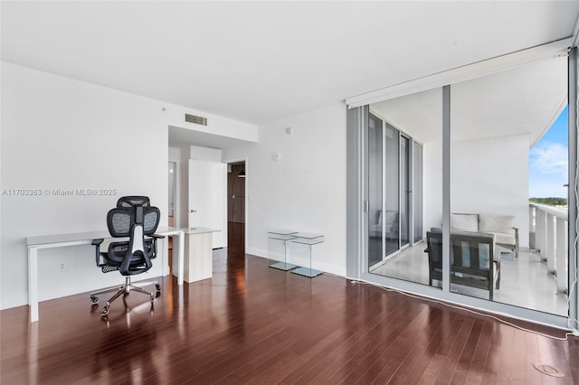 home office with expansive windows and dark hardwood / wood-style flooring