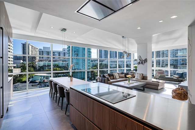 kitchen featuring tile patterned flooring, decorative light fixtures, a wall of windows, and black electric cooktop