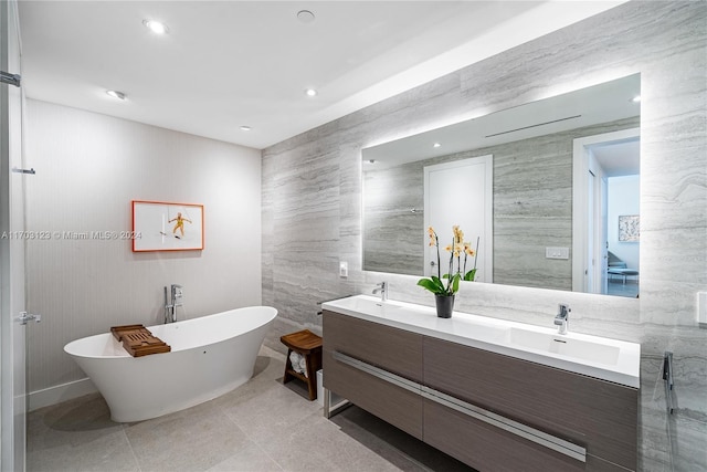 bathroom featuring a bathing tub, tile patterned flooring, vanity, and tile walls