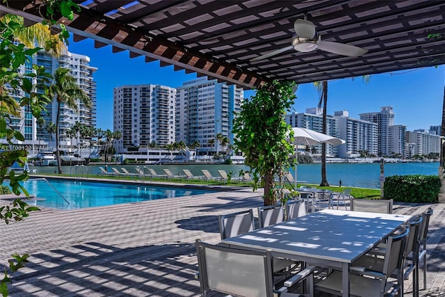 view of swimming pool with ceiling fan, a patio area, a pergola, and a water view