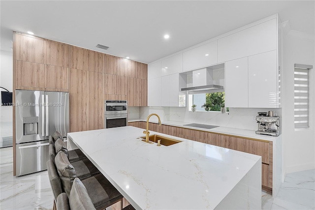 kitchen featuring wall chimney range hood, sink, a kitchen bar, white cabinetry, and stainless steel appliances