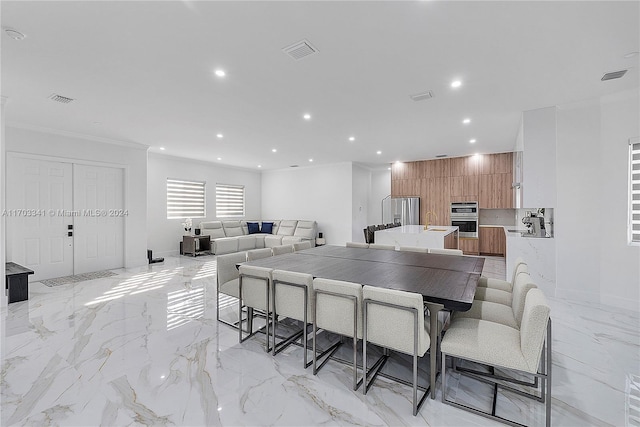 kitchen featuring a center island, sink, crown molding, double oven, and a breakfast bar area