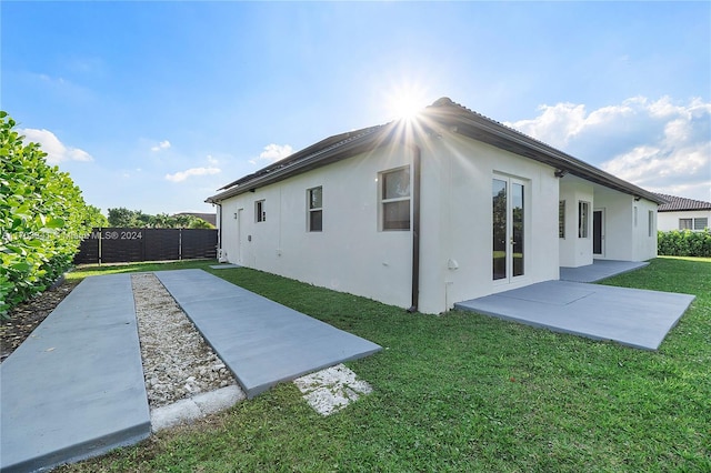 rear view of property featuring a yard and a patio area