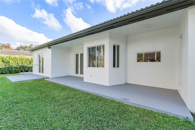 rear view of property with a yard, a patio, and french doors