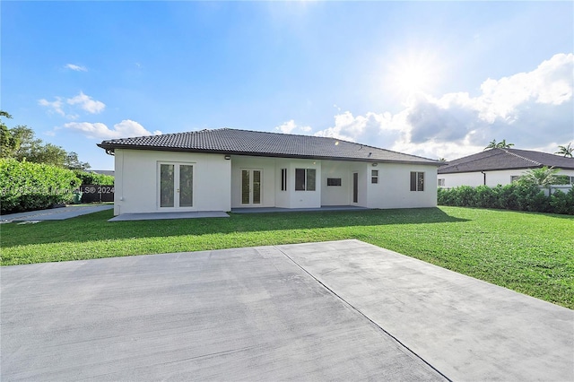 back of property with french doors, a patio, and a lawn