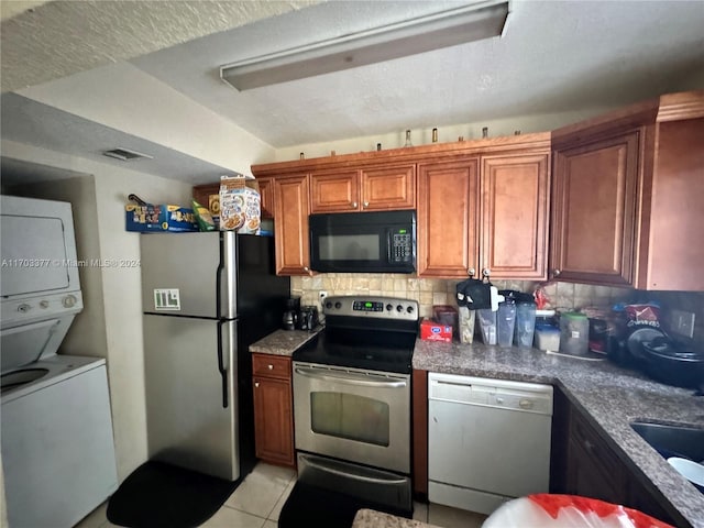 kitchen with a textured ceiling, stacked washer / drying machine, decorative backsplash, light tile patterned floors, and appliances with stainless steel finishes