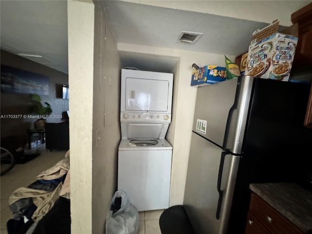 laundry area featuring light tile patterned floors and stacked washer and clothes dryer