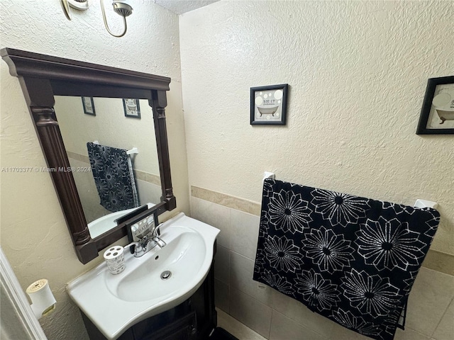 bathroom featuring vanity and tile walls