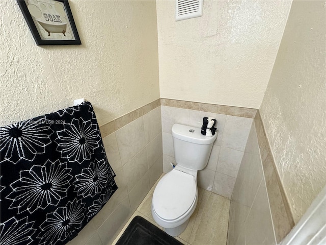 bathroom with toilet and tile walls