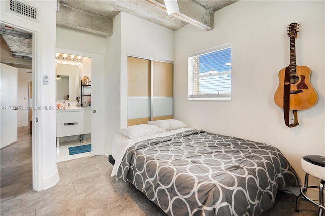 bedroom featuring ensuite bath, light tile patterned floors, and a closet