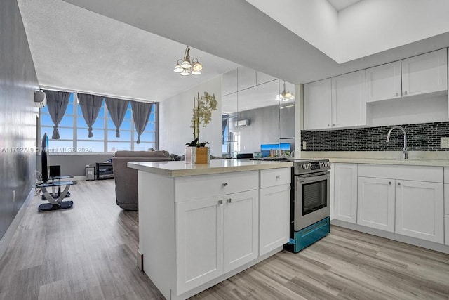 kitchen featuring decorative backsplash, pendant lighting, electric range, white cabinets, and light hardwood / wood-style floors