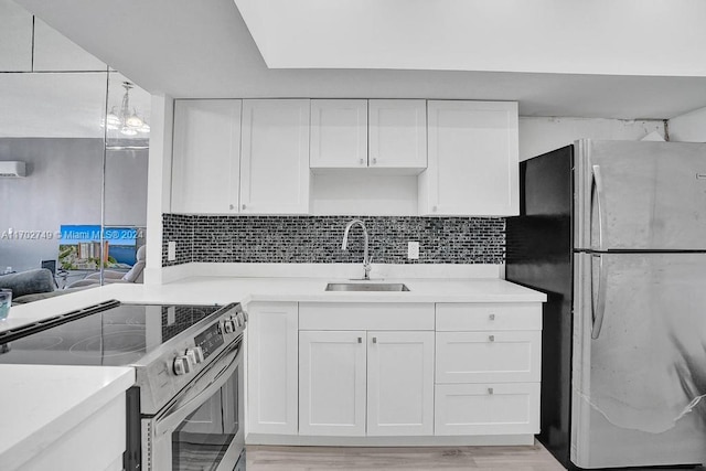 kitchen with appliances with stainless steel finishes, light wood-type flooring, tasteful backsplash, sink, and white cabinets