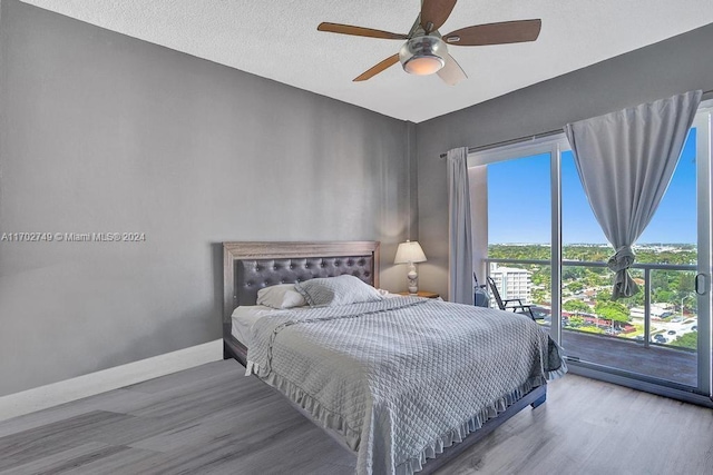 bedroom featuring hardwood / wood-style floors, a textured ceiling, access to outside, and ceiling fan