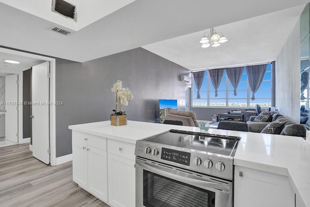 kitchen featuring stainless steel range with electric stovetop, a wall mounted air conditioner, white cabinets, light hardwood / wood-style flooring, and a notable chandelier