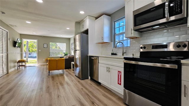 kitchen featuring light wood-type flooring, stainless steel appliances, white cabinetry, and sink