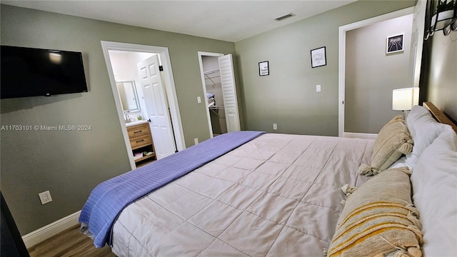 bedroom featuring wood-type flooring, a walk in closet, ensuite bath, and a closet