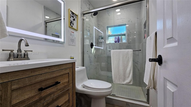 bathroom featuring vanity, a shower with shower door, and toilet