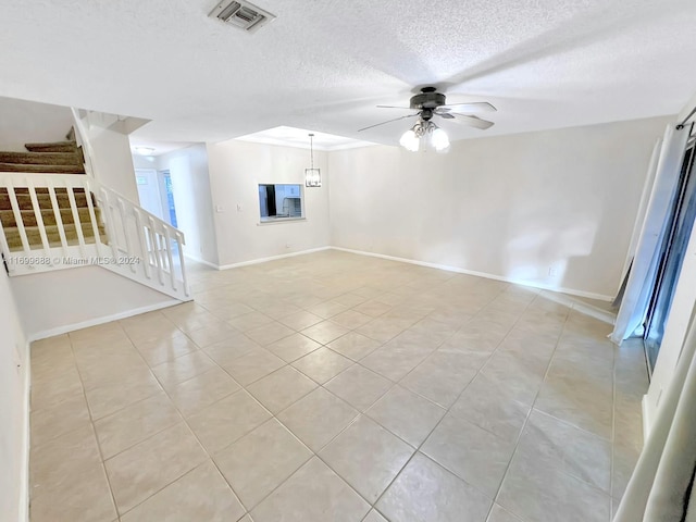 spare room with ceiling fan, light tile patterned flooring, and a textured ceiling