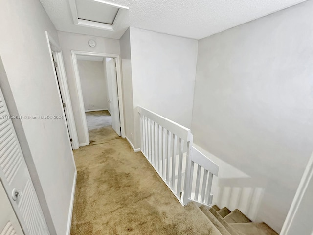 hallway featuring a textured ceiling and light carpet