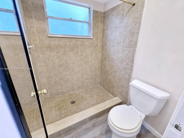 bathroom featuring a tile shower, hardwood / wood-style flooring, and toilet