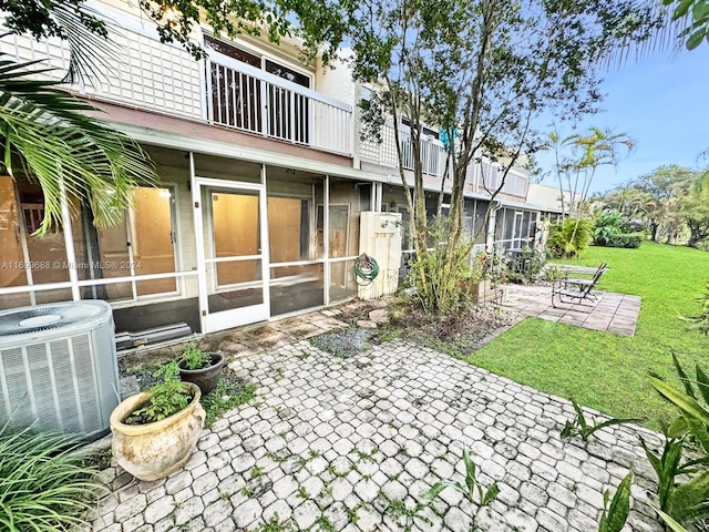 back of house featuring a yard, a patio, a sunroom, and central air condition unit