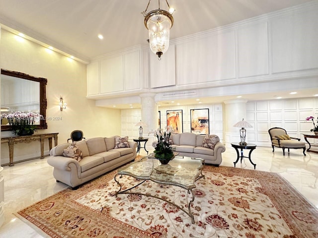 living room with an inviting chandelier, ornate columns, and crown molding