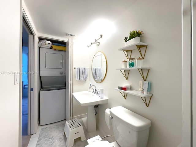 bathroom with stacked washer and dryer and toilet