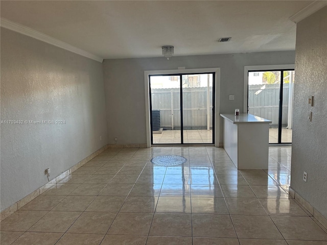 spare room featuring light tile patterned flooring, crown molding, and a wealth of natural light