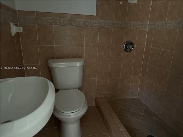 bathroom featuring tiled shower, tile patterned floors, tile walls, and toilet