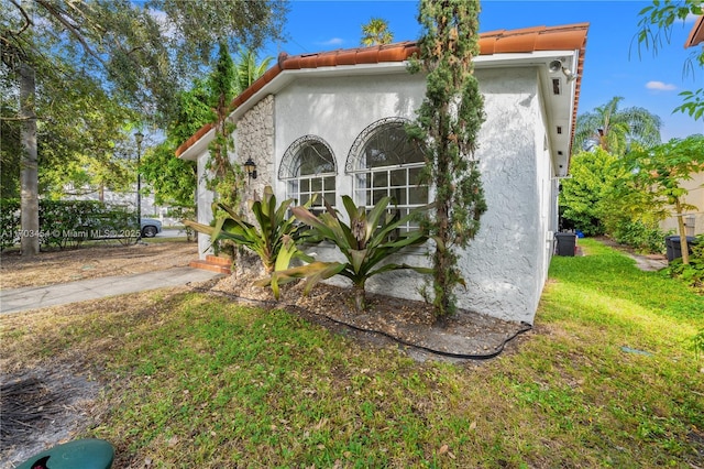 view of property exterior with stucco siding, a tile roof, and a yard