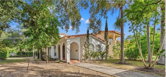mediterranean / spanish house featuring a tile roof and stucco siding