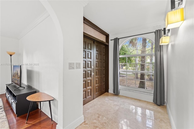 interior space featuring baseboards, arched walkways, and ornamental molding
