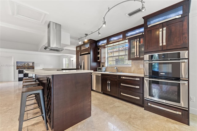 kitchen with island range hood, appliances with stainless steel finishes, a kitchen island, and light countertops