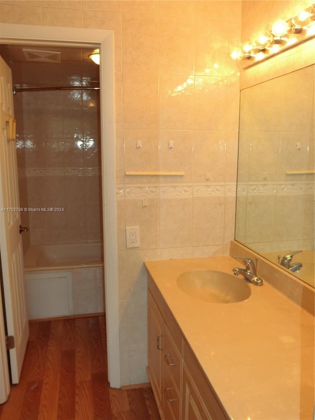 bathroom featuring wood-type flooring, vanity, and tile walls