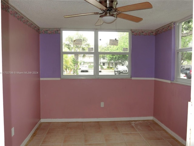 tiled empty room featuring ceiling fan and a textured ceiling