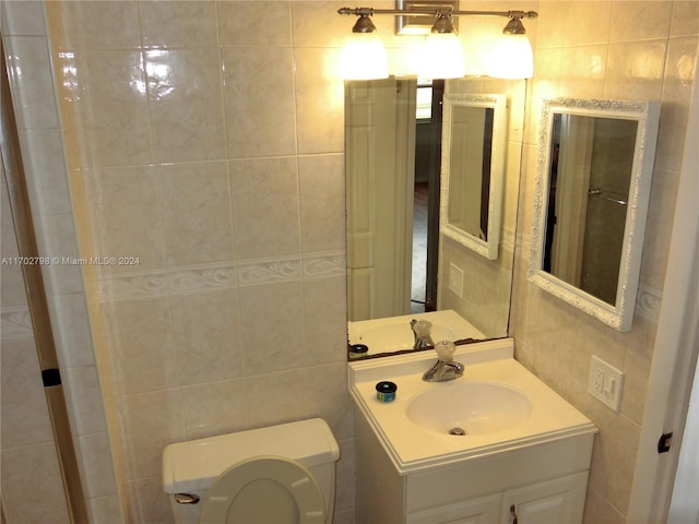 bathroom with vanity, toilet, and tile walls