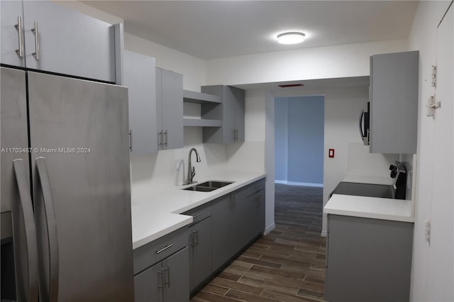 kitchen featuring appliances with stainless steel finishes, dark hardwood / wood-style floors, gray cabinets, and sink