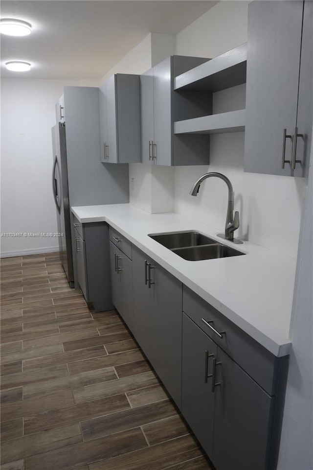 kitchen with gray cabinets, stainless steel fridge with ice dispenser, and sink