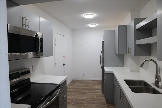 kitchen with stainless steel appliances, hardwood / wood-style flooring, gray cabinetry, and sink