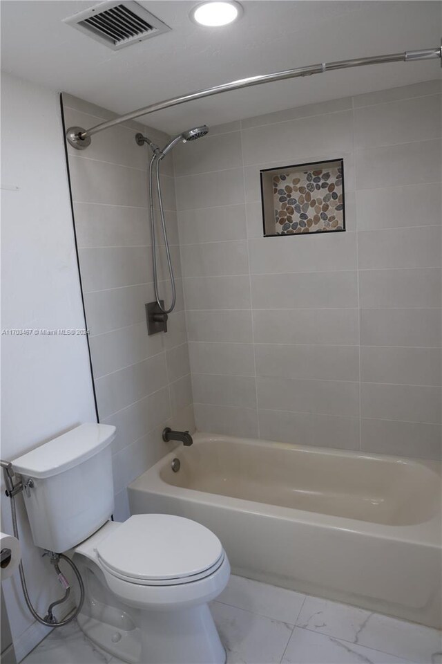 bathroom featuring tiled shower / bath combo and toilet