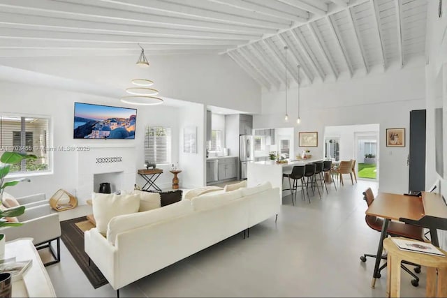 living area with lofted ceiling with beams, concrete floors, and a fireplace