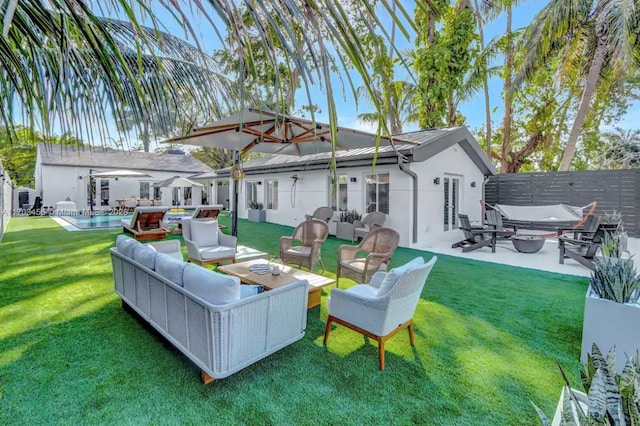 rear view of property featuring a lawn, an outdoor living space, and a patio area