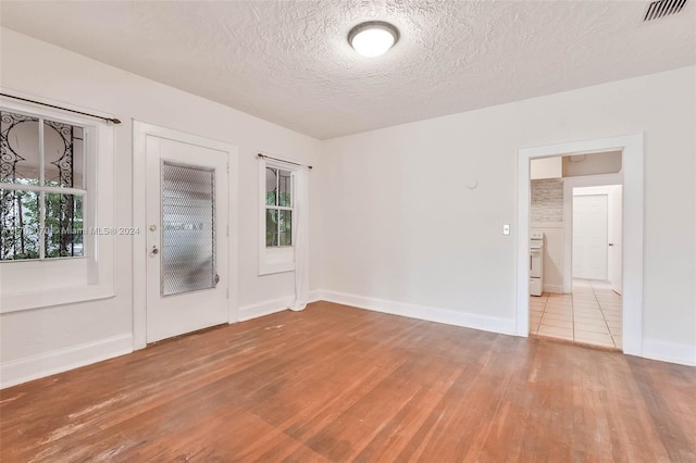 unfurnished room featuring light hardwood / wood-style floors and a textured ceiling