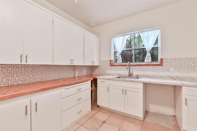 kitchen with white cabinets, backsplash, sink, and tile counters