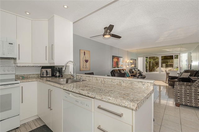 kitchen featuring kitchen peninsula, a textured ceiling, white appliances, and sink