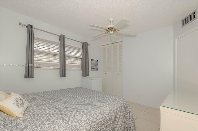 tiled bedroom featuring ceiling fan, a closet, and a textured ceiling